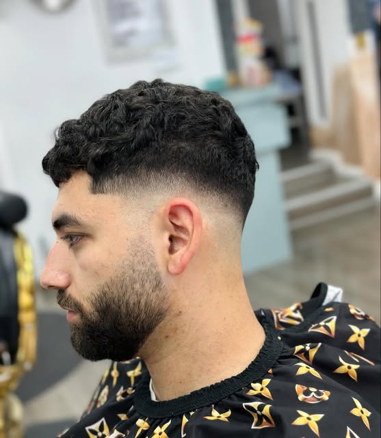 A carefully blended skin fade with a textured top and shaped beard